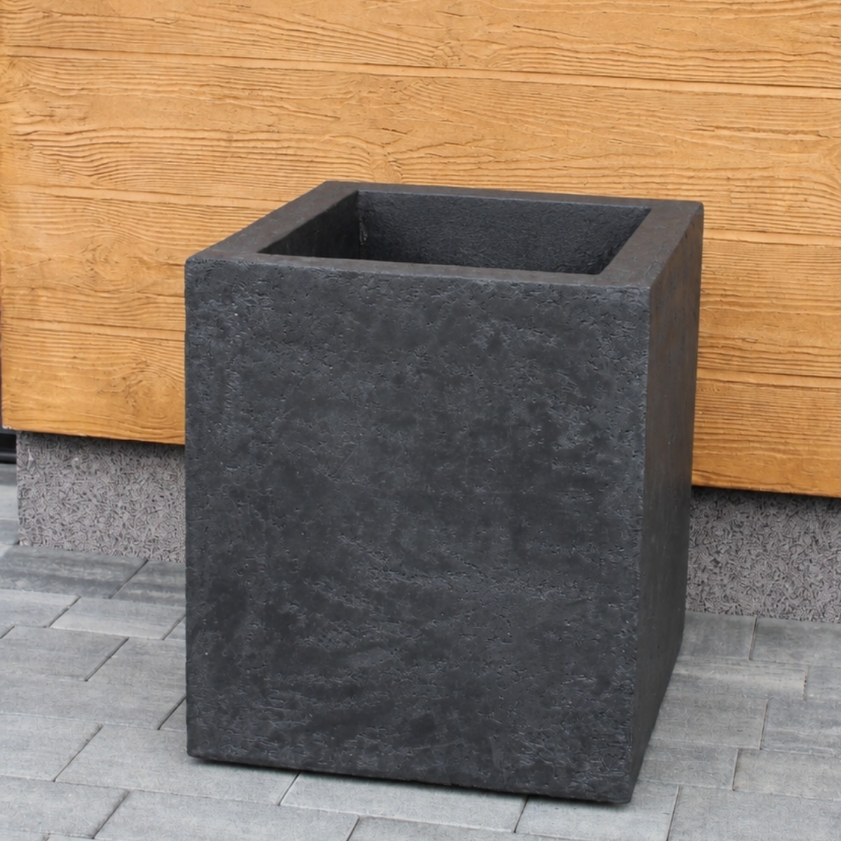 Antracytowa kwadratowa TERMODONICA TD-50 CUBE przy drewnianej elewacji